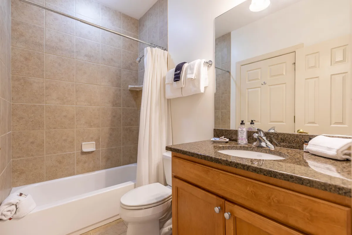 A serene bathroom featuring a deep bathtub, a vanity with a large mirror, and a tranquil mood. The setup suggests a soothing retreat for unwinding after outdoor adventures.