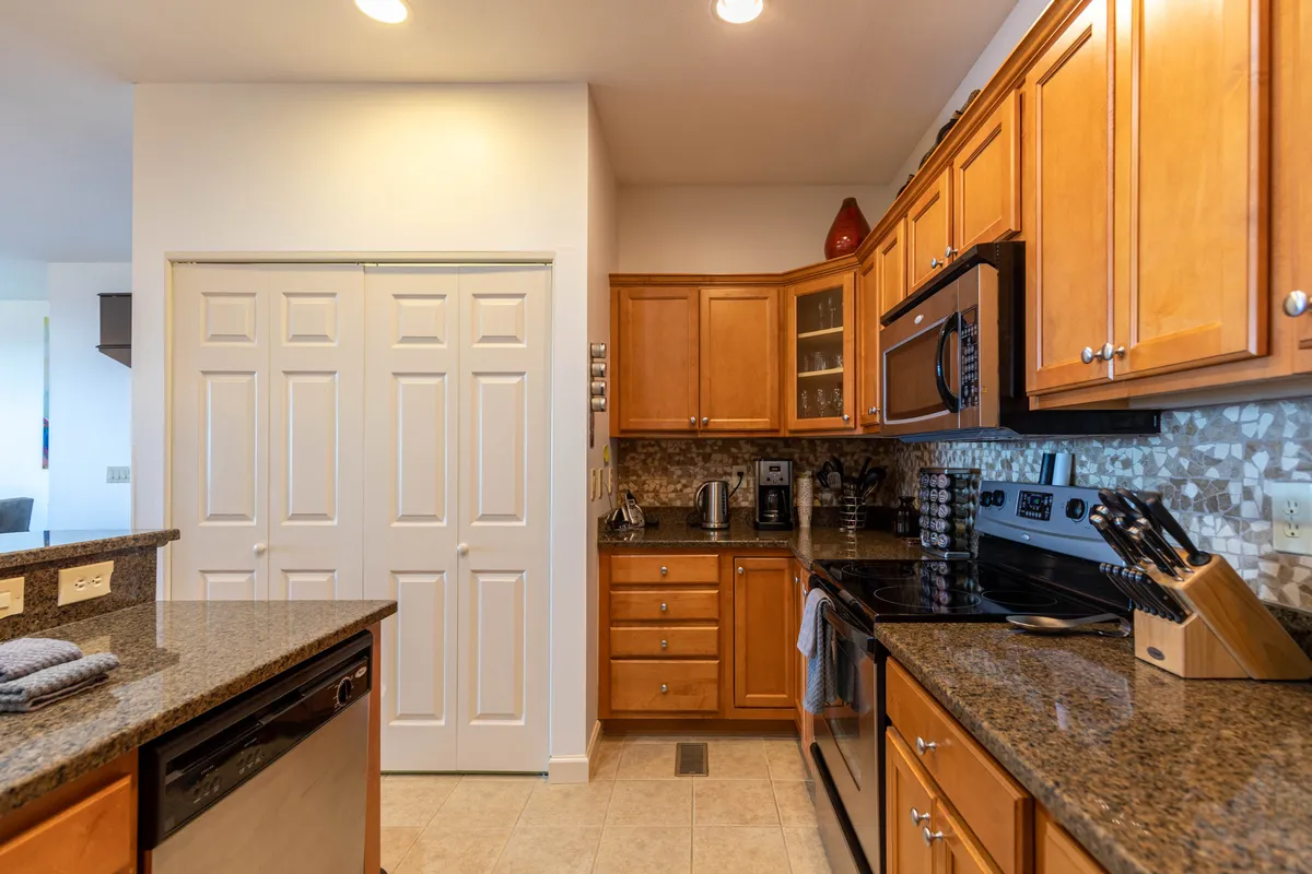 This kitchen shot features granite countertops, warm wooden cabinetry, and modern appliances, set up for cooking and entertaining. The inviting mood underscores togetherness, with ample space for meal prep and hosting family or friends.