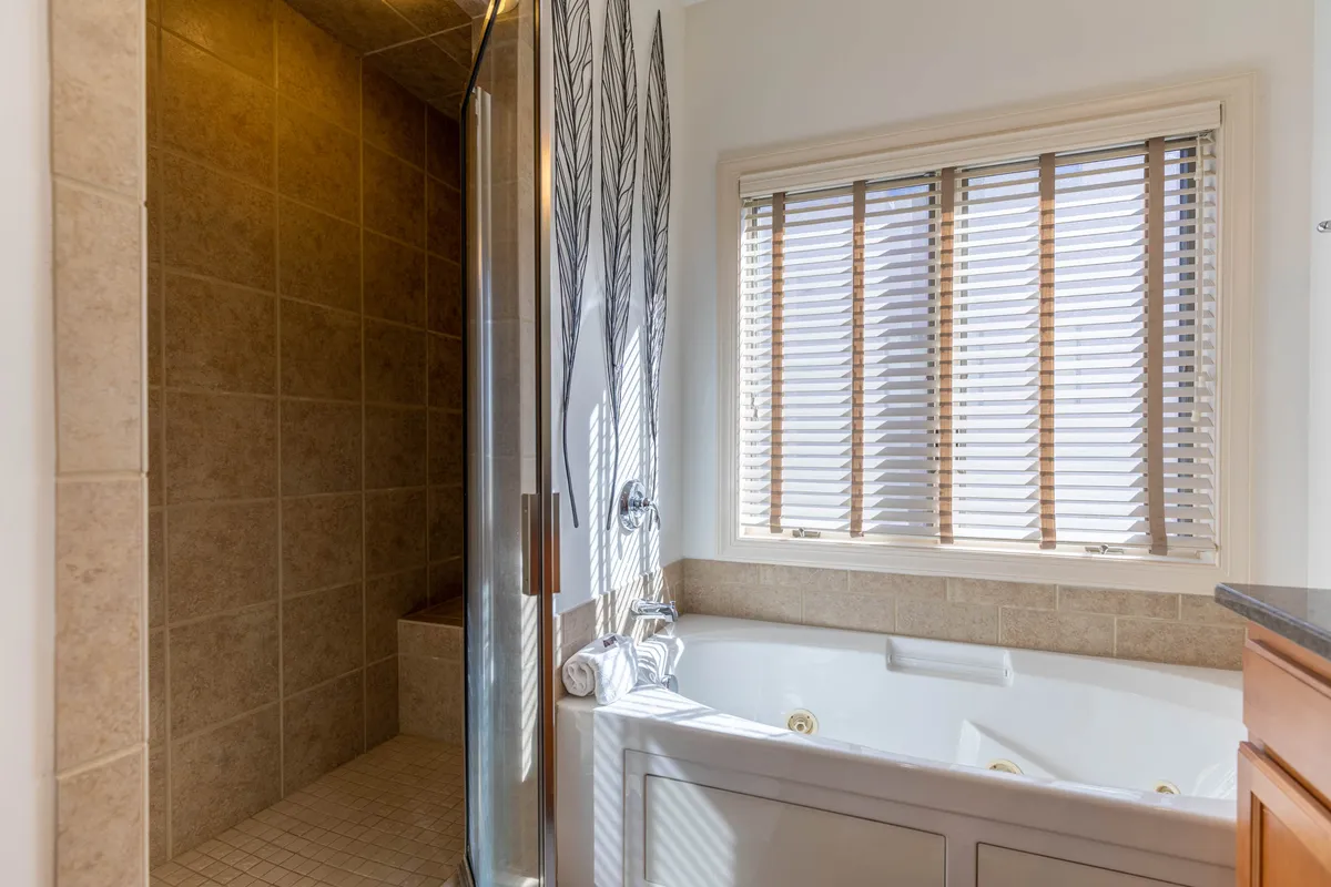 A tranquil interior bathroom featuring a modern jetted bathtub, decorative wall design, and a window that lets in natural light. The scene suggests a relaxing retreat after an active day outdoors, linking the comfort of the condo to the adventure outside.