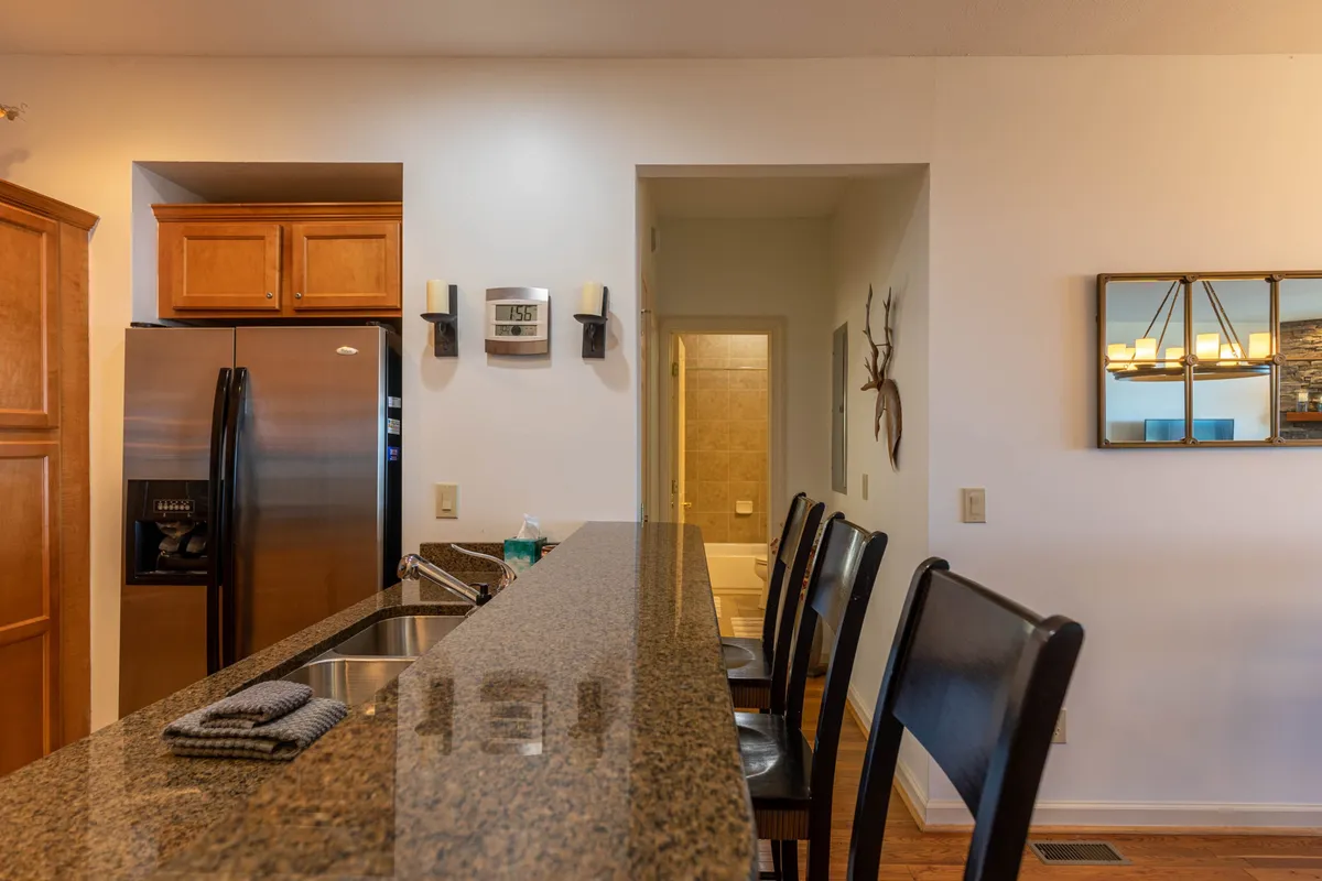 A cozy kitchen nook with granite countertops, stainless steel appliances, wooden cabinets, and a line of bar stools. The layout encourages casual breakfasts or late-night snacks, with everything you need within easy reach.